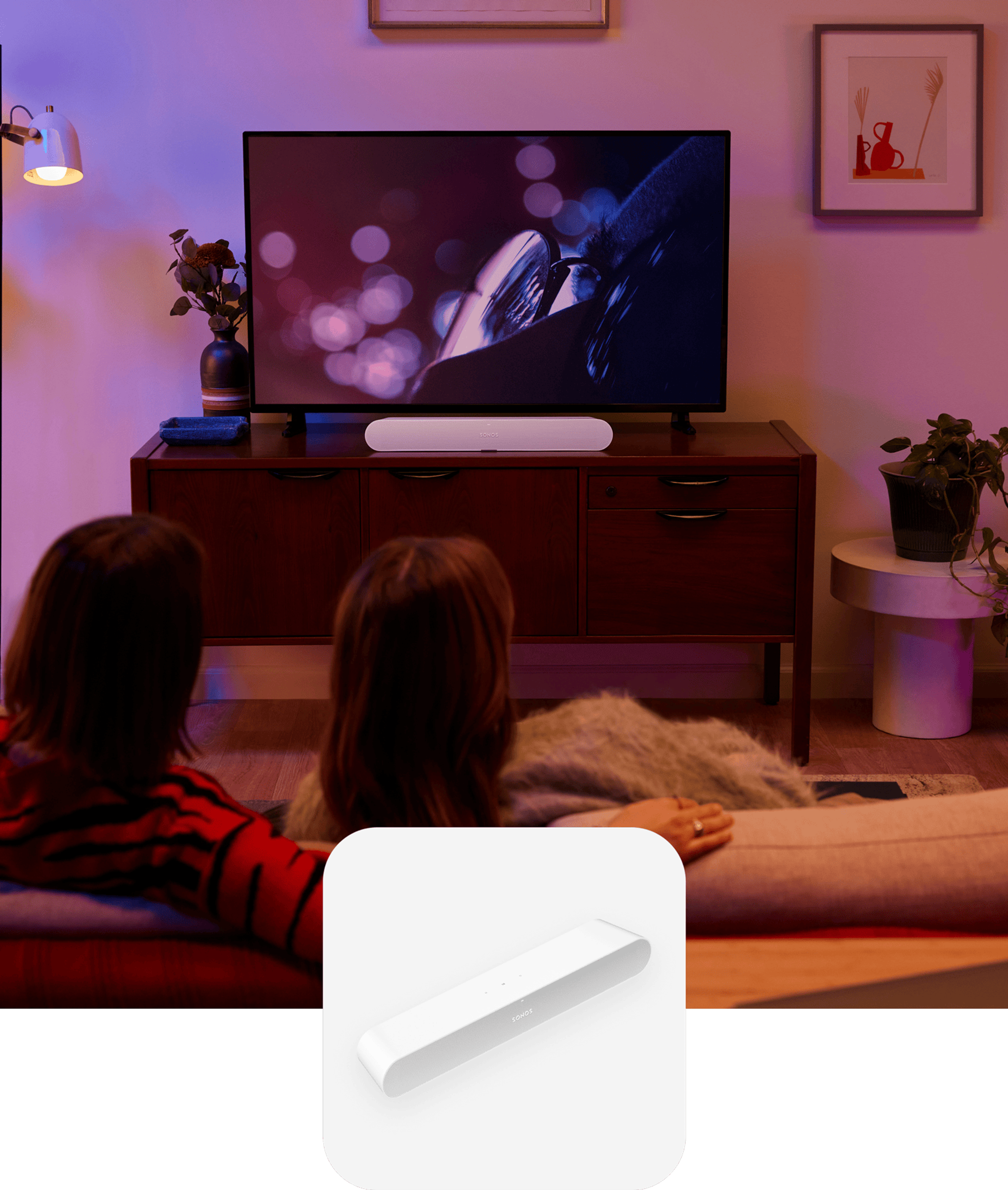 Couple on the couch in their living room watching a movie with sound from a white Sonos Ray soundbar