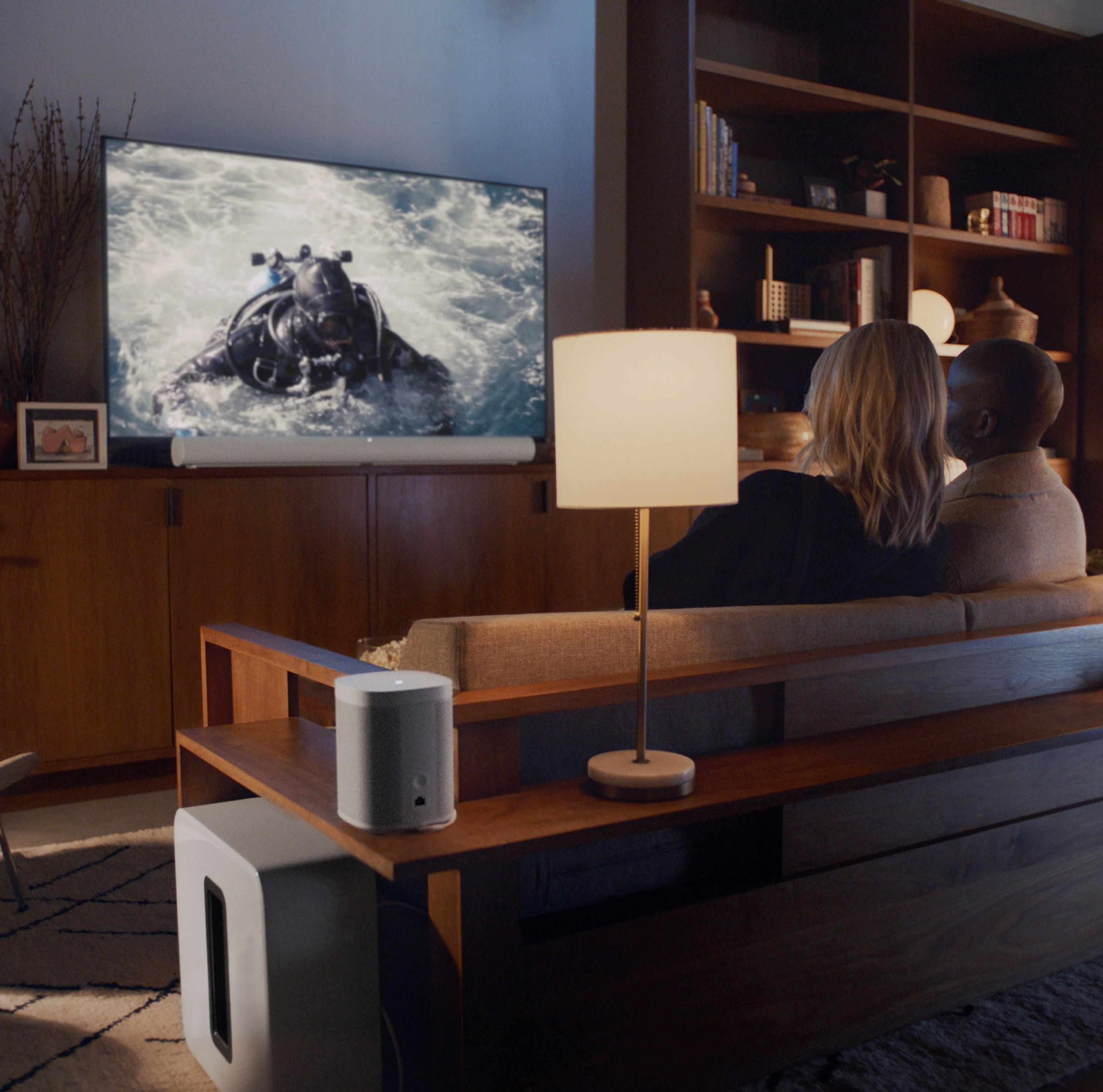 使用白色Sonos Arc家庭影院系统观看电视的夫妻