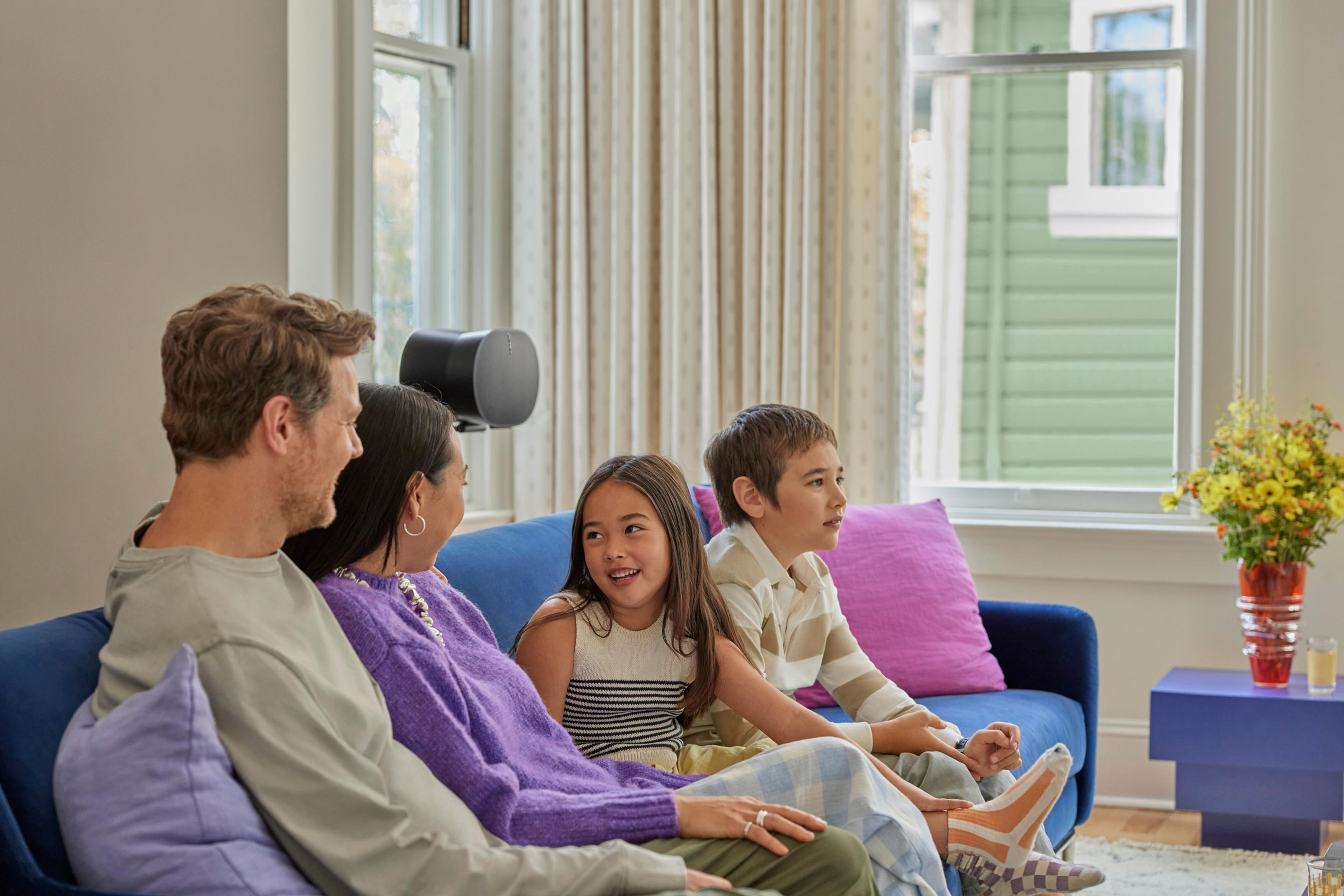 Family seated on blue couch listening to their Sonos home theater system