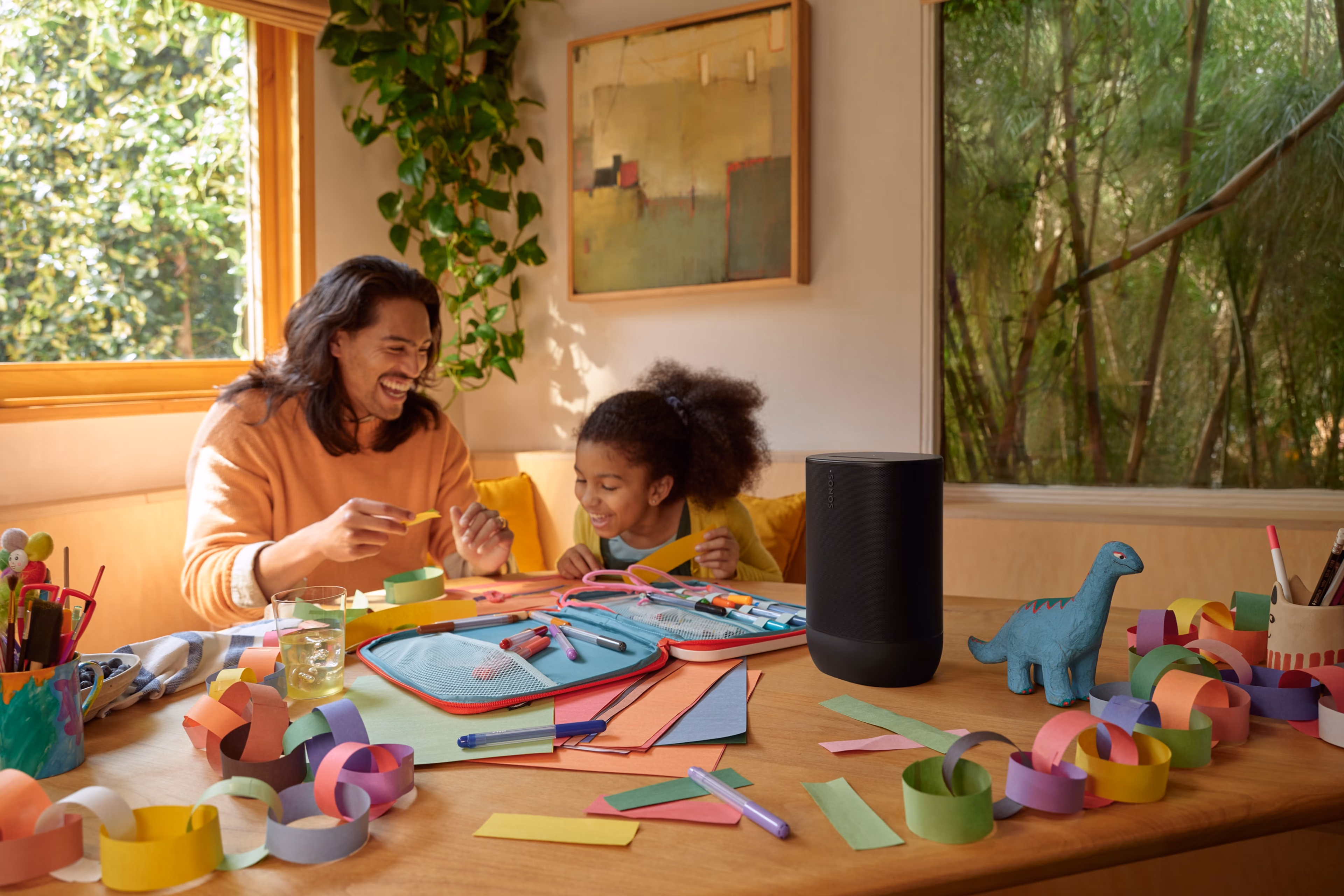 A picture of a father and daughter at the kitchen table doing arts and crafts while listening to a black Sonos Move 2