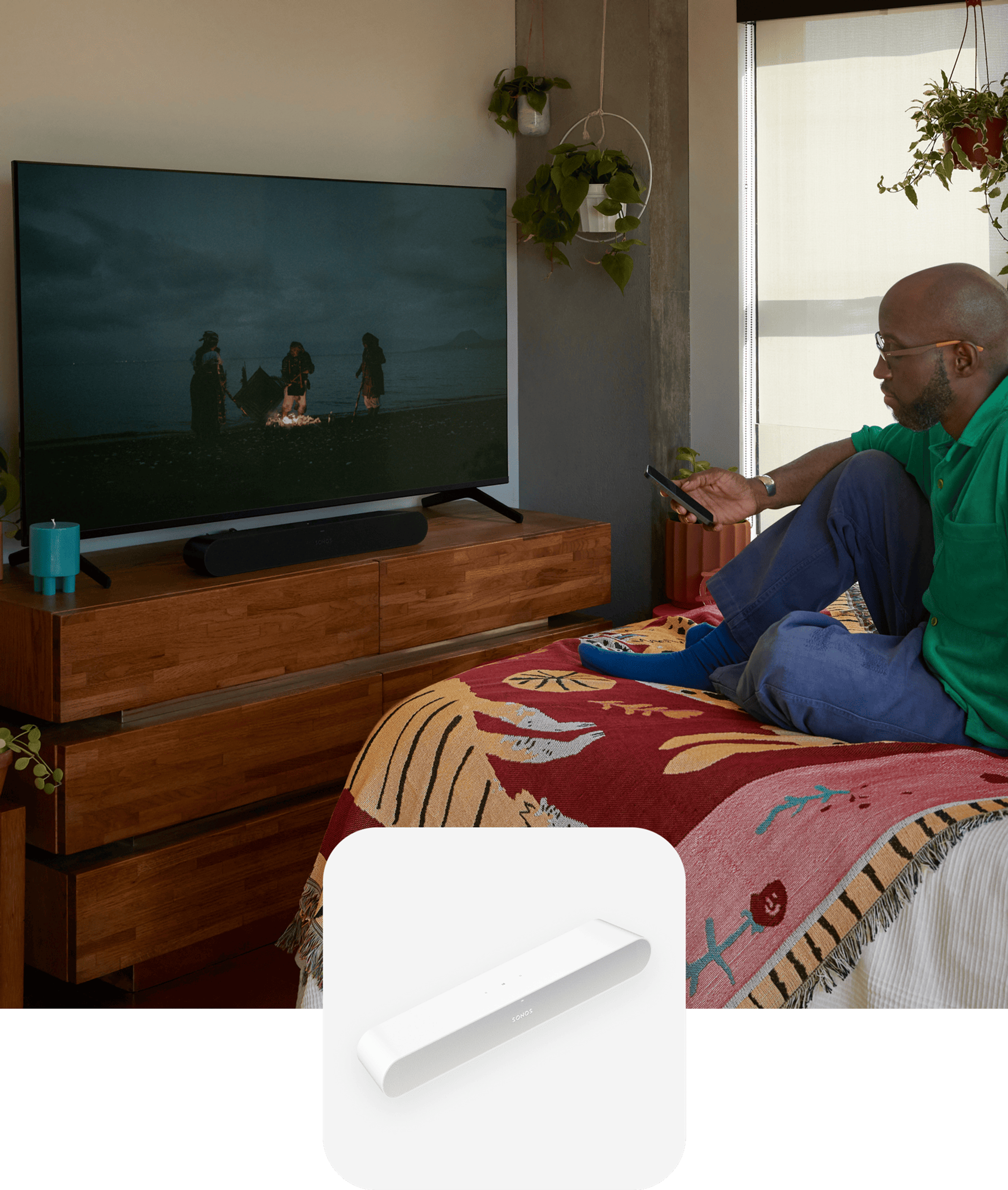 User sitting on their bed watching a movie with sound from a black Ray soundbar