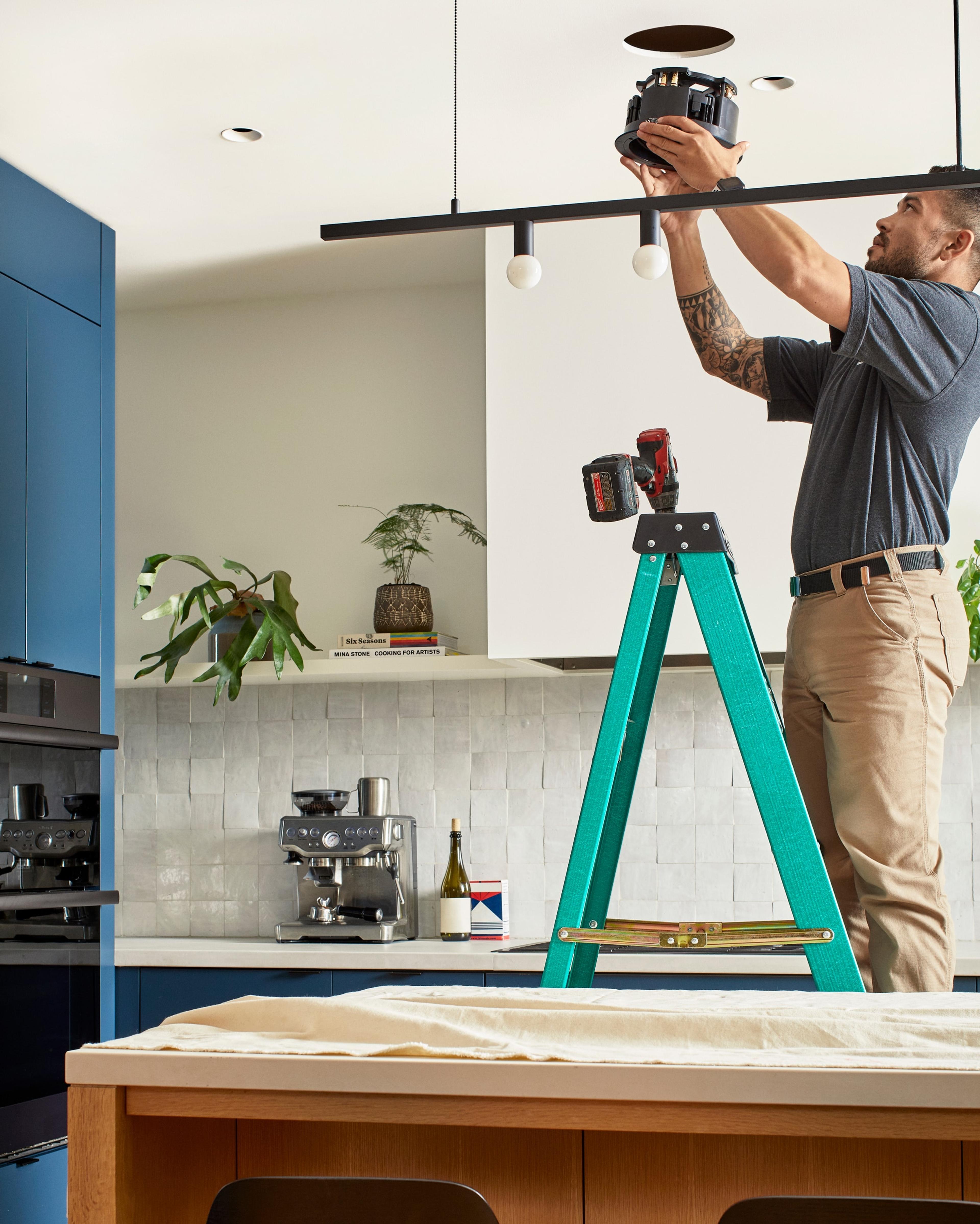 Professional installer installing Sonos and Sonance In-Ceiling speakers above kitchen island