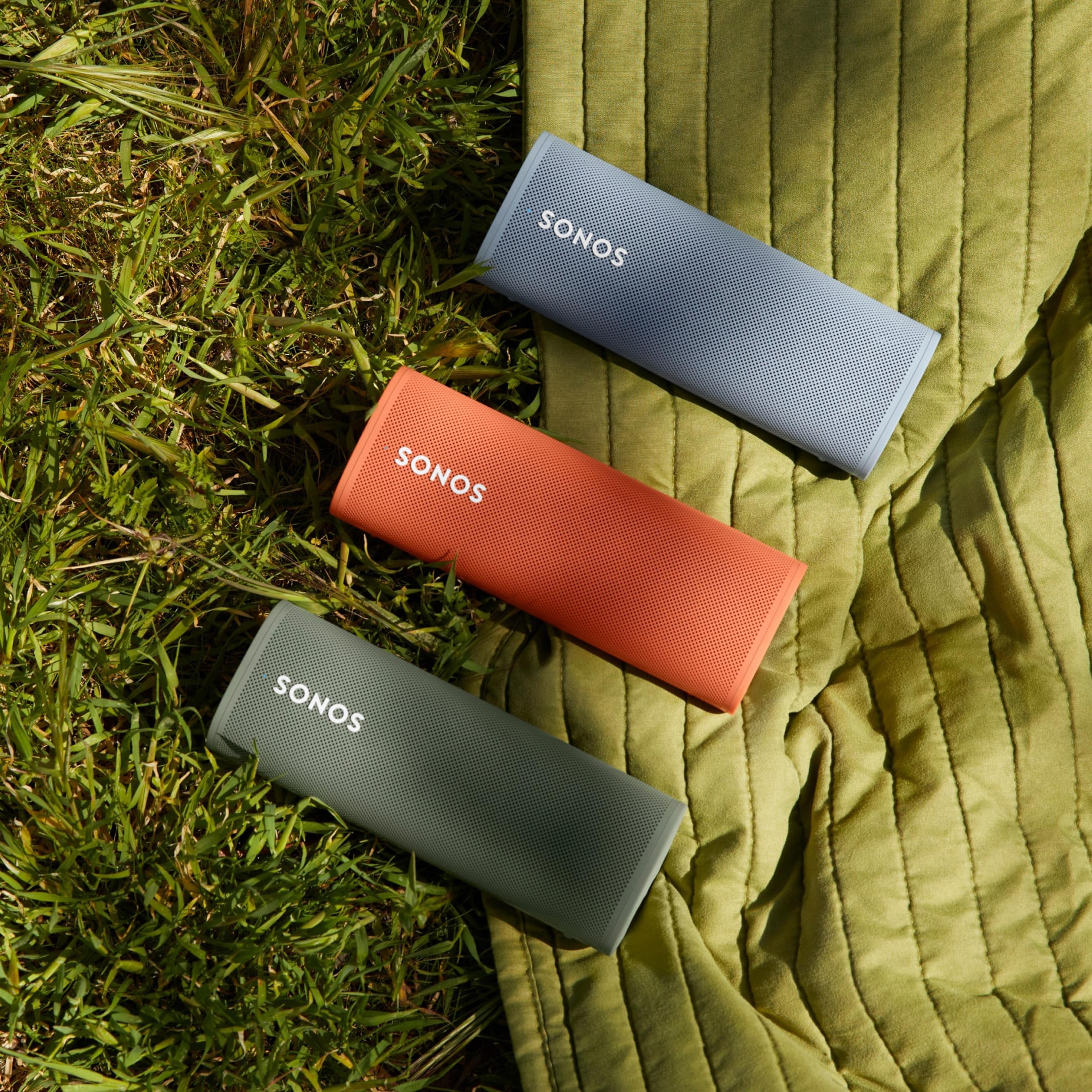 Roam speakers in Olive, Sunset, and Wave on grass 