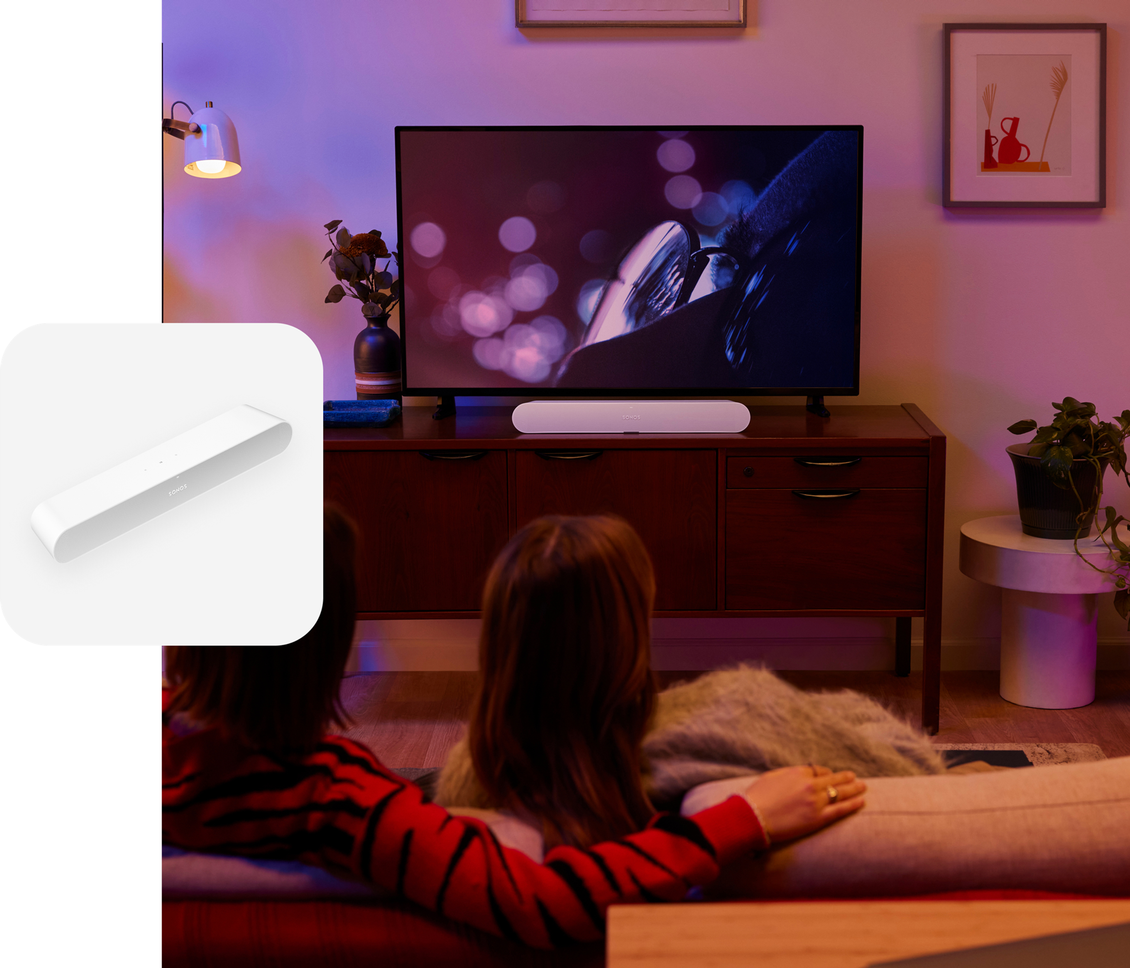 Couple on the couch in their living room watching a movie with sound from a white Sonos Ray soundbar